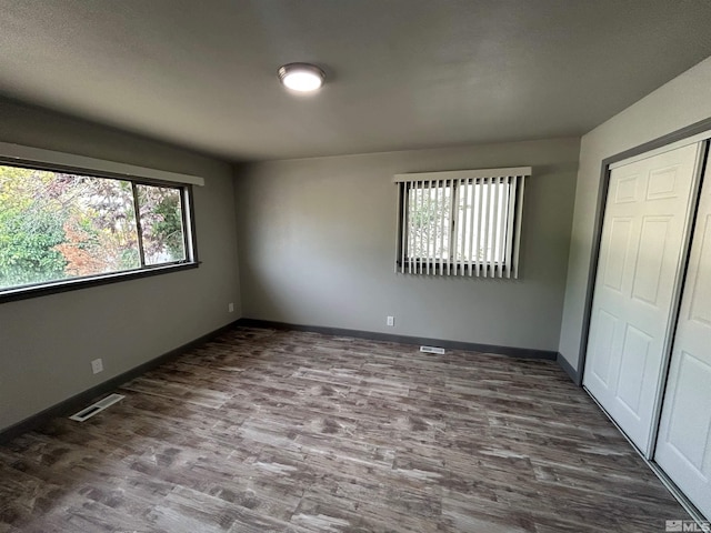 unfurnished bedroom featuring dark hardwood / wood-style flooring, lofted ceiling, and a closet