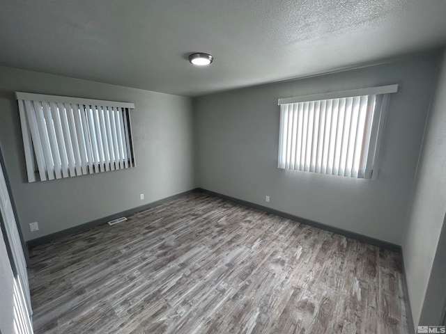 empty room with hardwood / wood-style floors and a textured ceiling