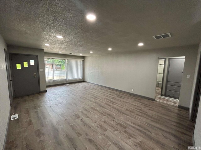 spare room featuring a textured ceiling and dark hardwood / wood-style floors