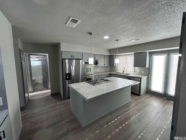 kitchen with dark hardwood / wood-style flooring, a kitchen island, gray cabinetry, appliances with stainless steel finishes, and sink