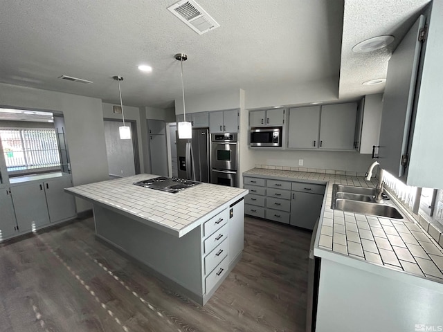 kitchen with sink, dark wood-type flooring, appliances with stainless steel finishes, gray cabinetry, and a kitchen island