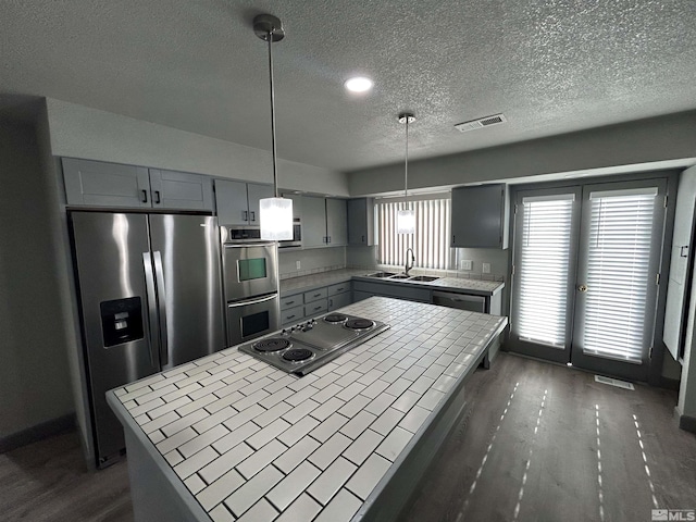 kitchen featuring pendant lighting, sink, gray cabinets, appliances with stainless steel finishes, and a center island