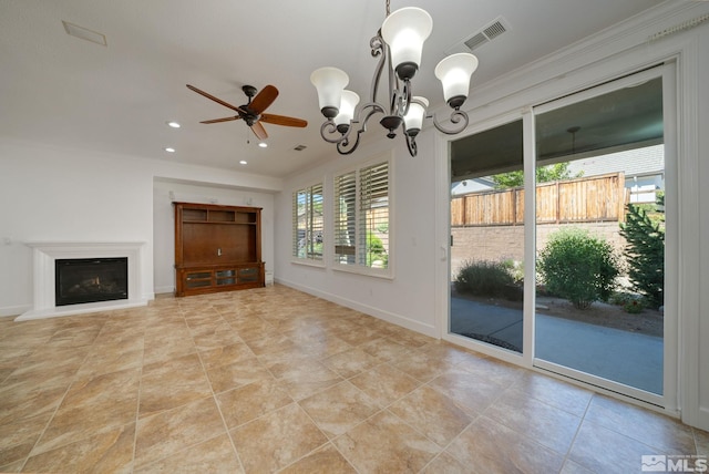 unfurnished living room featuring ornamental molding, ceiling fan with notable chandelier, and a healthy amount of sunlight