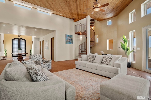 living room with a towering ceiling, wood ceiling, ceiling fan, and light tile floors