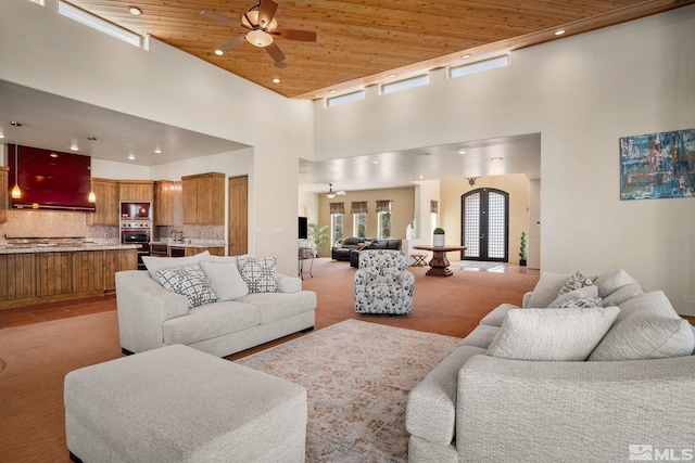 tiled living room featuring ceiling fan, a towering ceiling, and wood ceiling