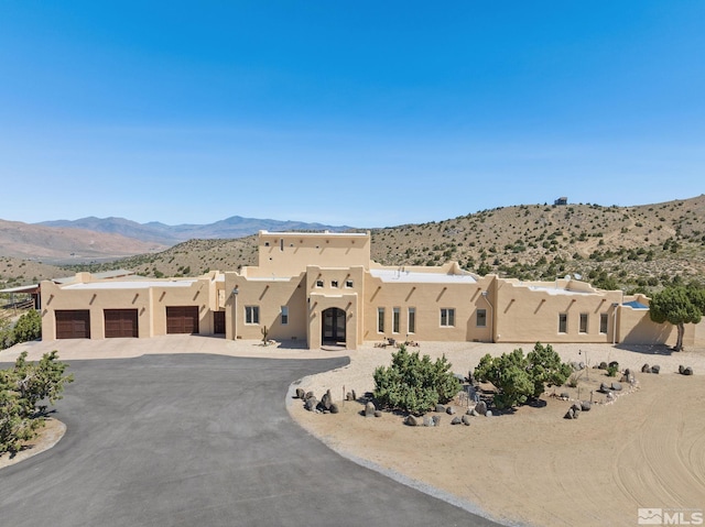 pueblo-style house with a garage and a mountain view