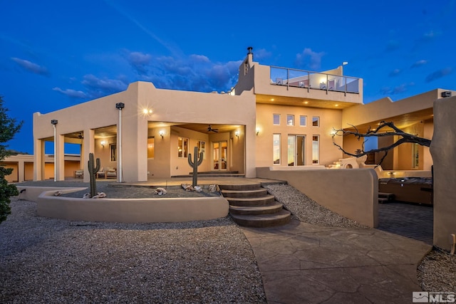 back house at night with a patio area and a balcony