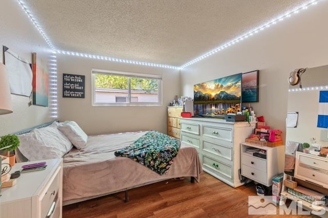 bedroom with light hardwood / wood-style flooring and a textured ceiling