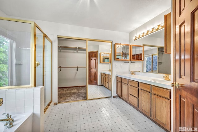 bathroom with double vanity, tile patterned floors, a sink, a shower stall, and a wealth of natural light