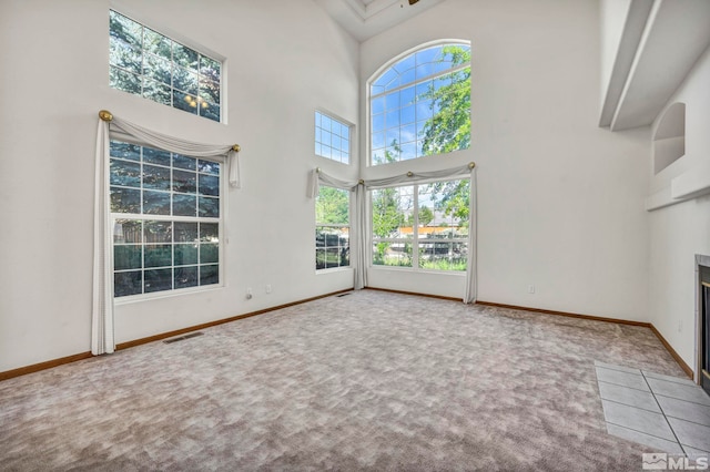 unfurnished living room with carpet, a towering ceiling, and a fireplace