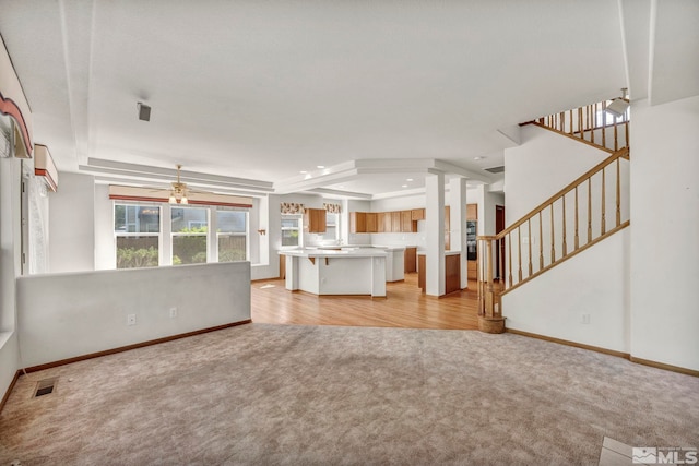 unfurnished living room with ceiling fan, light carpet, and a tray ceiling