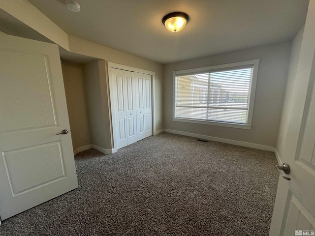 unfurnished bedroom featuring dark carpet and a closet