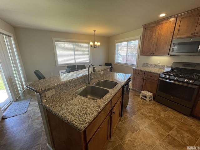 kitchen with appliances with stainless steel finishes, sink, a healthy amount of sunlight, and an island with sink