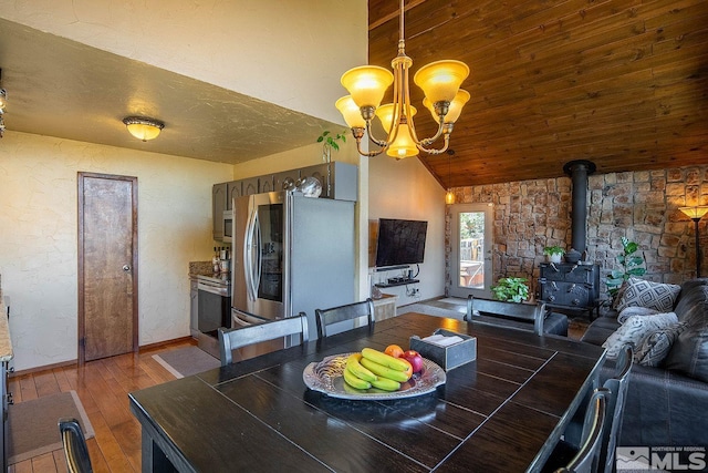 dining area featuring wood ceiling, a notable chandelier, hardwood / wood-style floors, a wood stove, and lofted ceiling