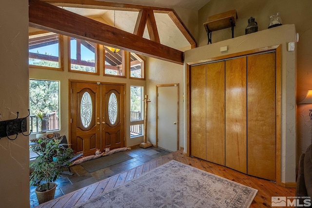 entryway featuring beamed ceiling, hardwood / wood-style floors, and high vaulted ceiling