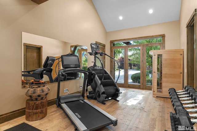 workout room with light hardwood / wood-style floors, high vaulted ceiling, and french doors