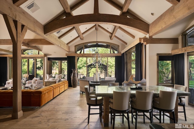 dining room with light wood-type flooring, a notable chandelier, and lofted ceiling with beams