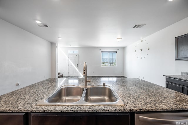 kitchen with sink, stainless steel dishwasher, and dark stone counters