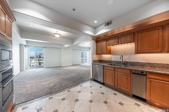 kitchen with appliances with stainless steel finishes, sink, dark stone counters, and light colored carpet