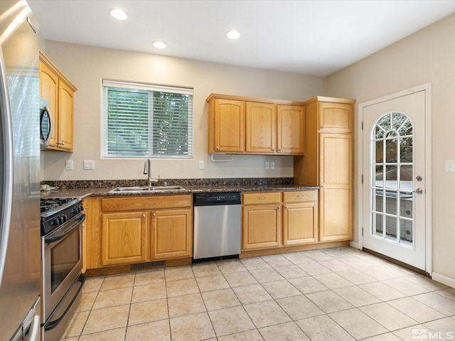 kitchen with sink, light tile patterned floors, stainless steel appliances, and dark stone counters