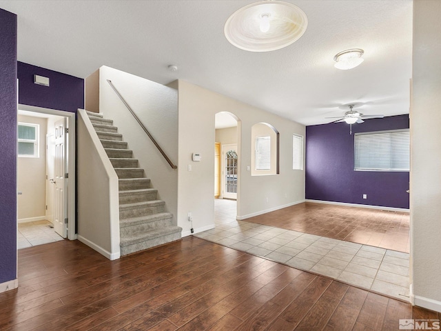 unfurnished living room featuring hardwood / wood-style floors, ceiling fan, and a textured ceiling