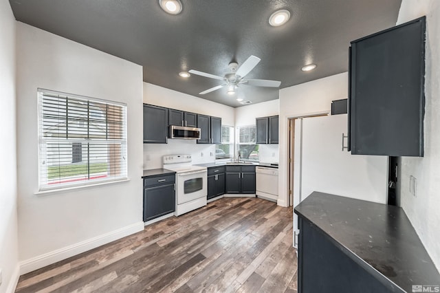 kitchen featuring a textured ceiling, white appliances, ceiling fan, sink, and dark hardwood / wood-style floors