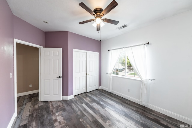 unfurnished bedroom with ceiling fan, a closet, and dark wood-type flooring