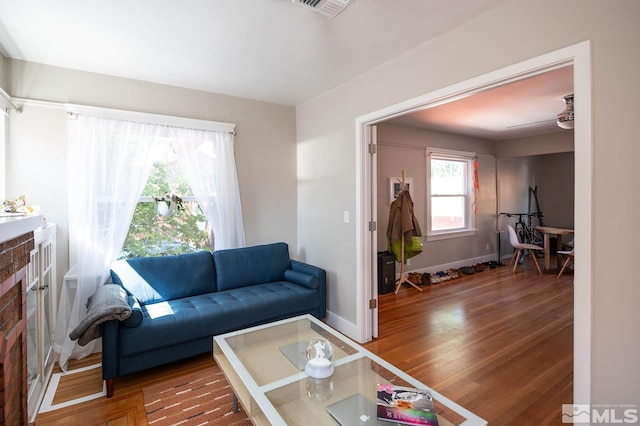 living area with visible vents, a fireplace, baseboards, and wood finished floors