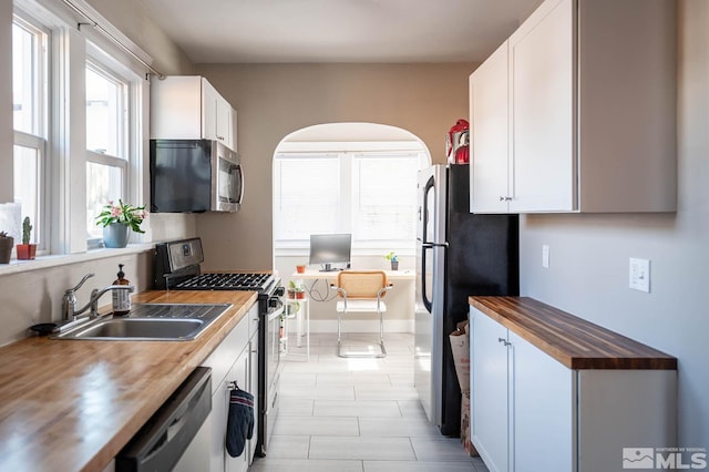 kitchen featuring white cabinetry, appliances with stainless steel finishes, wooden counters, and a sink