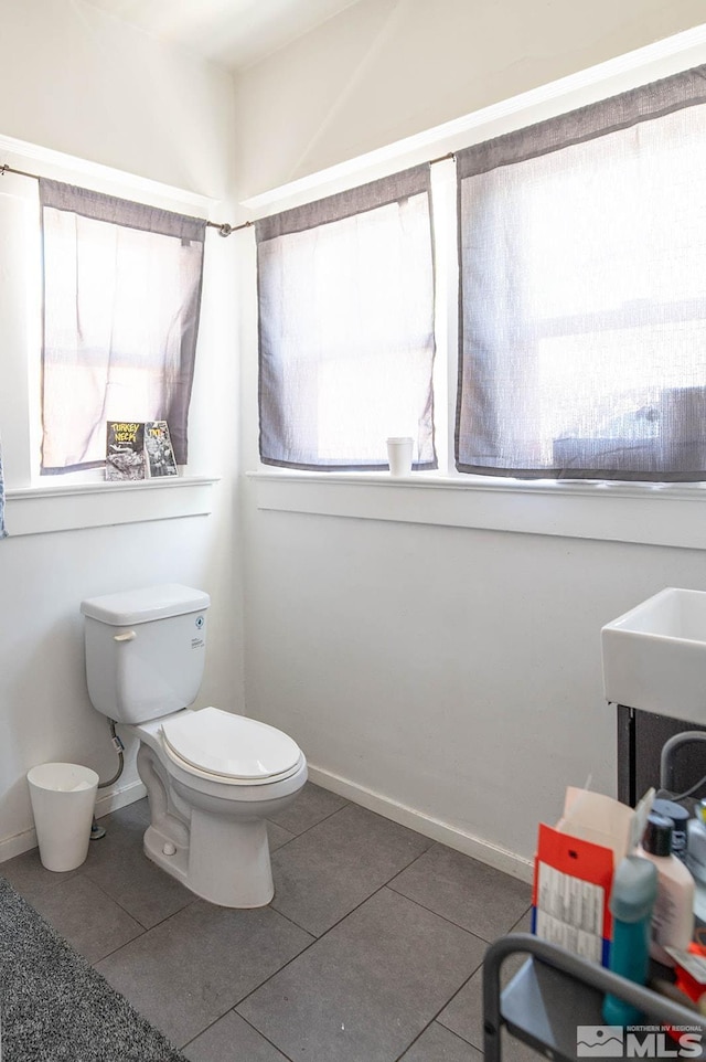 bathroom with toilet, tile patterned flooring, and baseboards