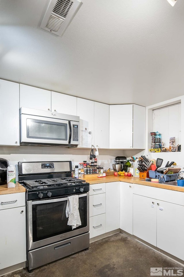 kitchen with white cabinets, butcher block countertops, and appliances with stainless steel finishes