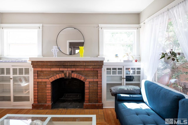 living room with hardwood / wood-style flooring, a brick fireplace, and a wealth of natural light