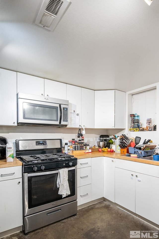 kitchen featuring stainless steel appliances, visible vents, concrete flooring, and white cabinetry