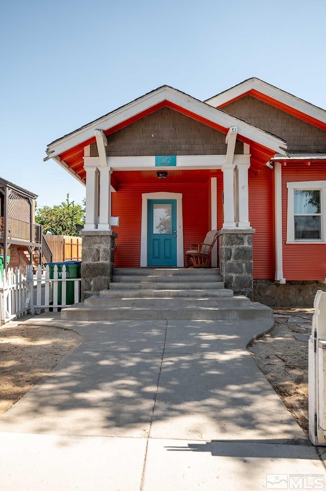 entrance to property featuring covered porch and fence