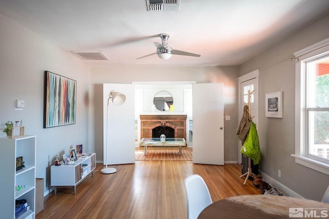 living room featuring a fireplace, wood-type flooring, and ceiling fan