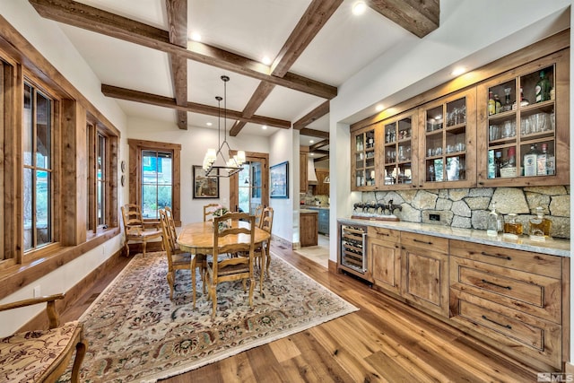 dining space featuring coffered ceiling, beverage cooler, hardwood / wood-style flooring, a notable chandelier, and beamed ceiling