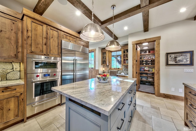 kitchen with gray cabinetry, a center island, light stone counters, backsplash, and appliances with stainless steel finishes