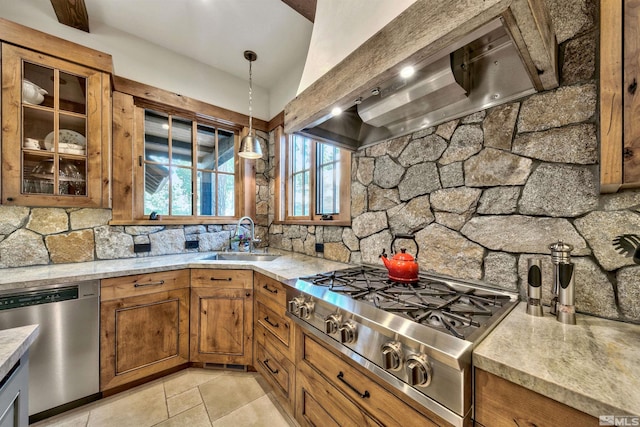 kitchen with light stone countertops, sink, hanging light fixtures, exhaust hood, and appliances with stainless steel finishes