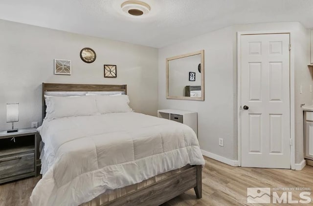 bedroom featuring a textured ceiling and light hardwood / wood-style floors