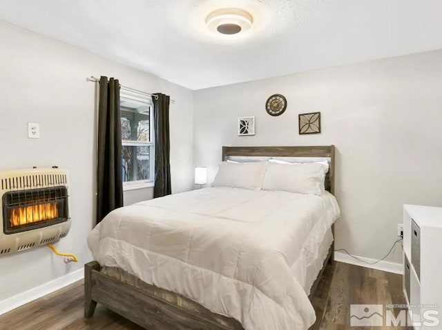 bedroom with dark hardwood / wood-style flooring, a textured ceiling, and heating unit