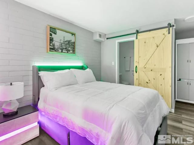 bedroom with dark hardwood / wood-style floors and a barn door