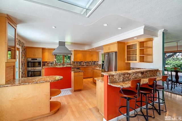 kitchen with appliances with stainless steel finishes, light wood-type flooring, island range hood, and crown molding