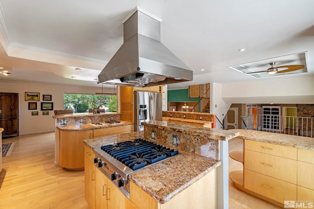 kitchen with light stone countertops, a center island, stainless steel appliances, kitchen peninsula, and island exhaust hood