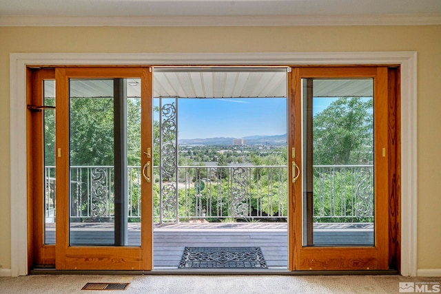 doorway to outside featuring a mountain view, carpet floors, and crown molding