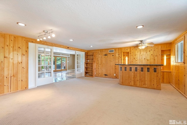 unfurnished living room with light carpet, french doors, ceiling fan, and a textured ceiling