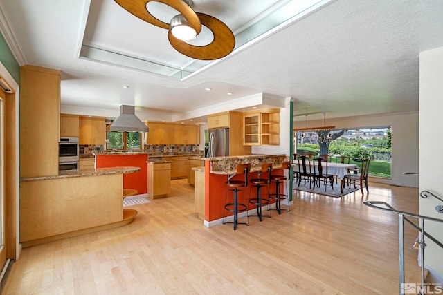 kitchen featuring appliances with stainless steel finishes, backsplash, a tray ceiling, crown molding, and a kitchen island