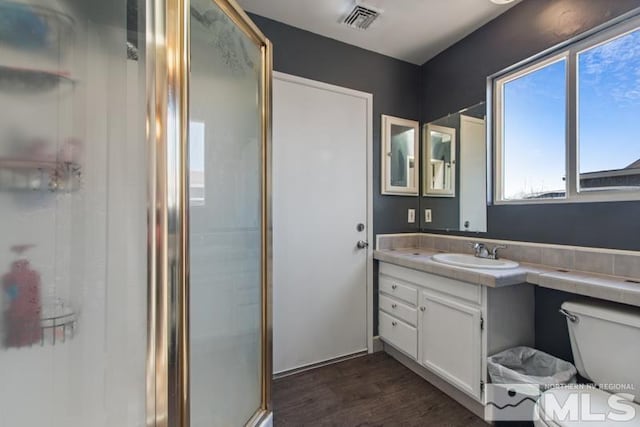 bathroom with hardwood / wood-style flooring, vanity, toilet, and a shower with door