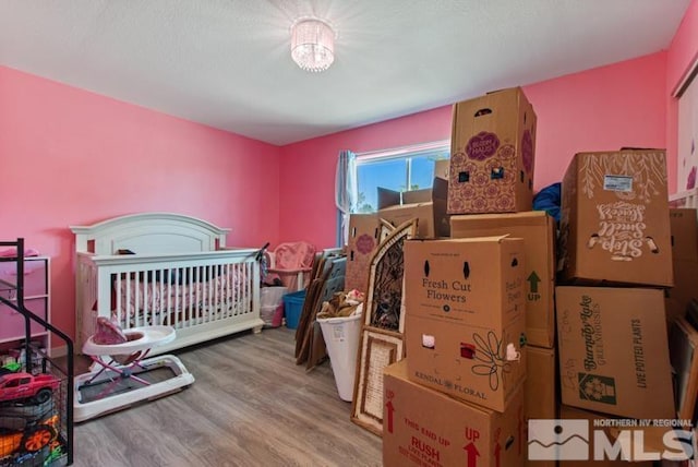 bedroom with hardwood / wood-style floors and a nursery area