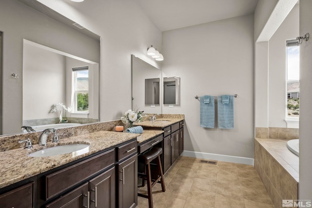 bathroom with visible vents, a sink, baseboards, and a bath