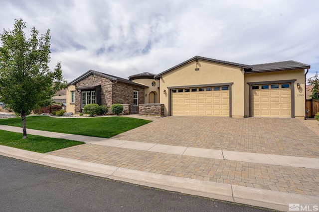 view of front of home with stucco siding, a tile roof, an attached garage, decorative driveway, and a front yard